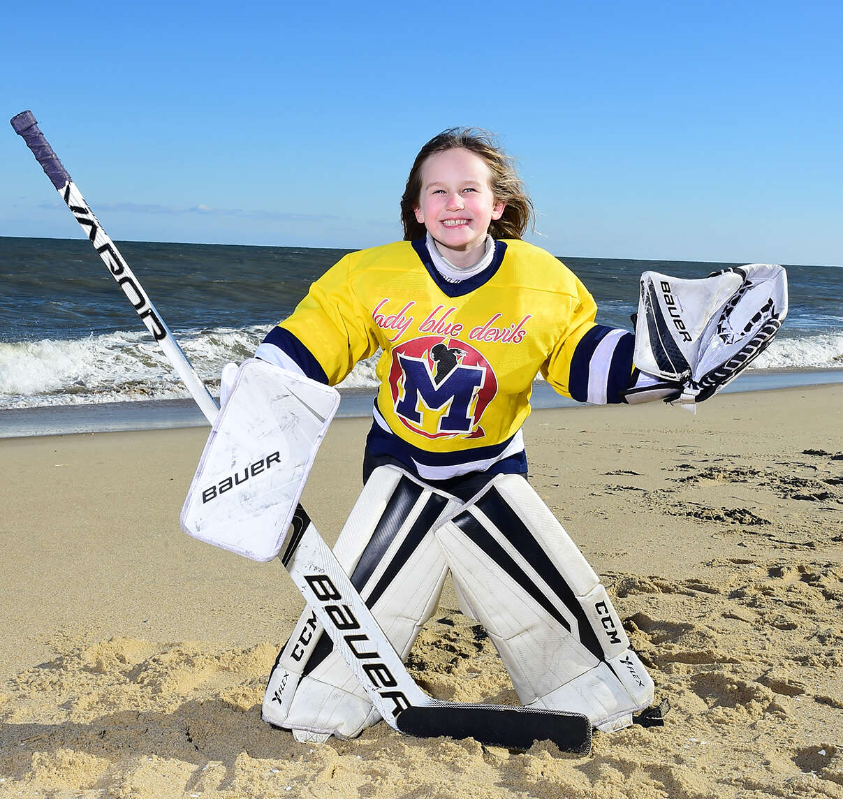 Child hockey goalie posing on the beach