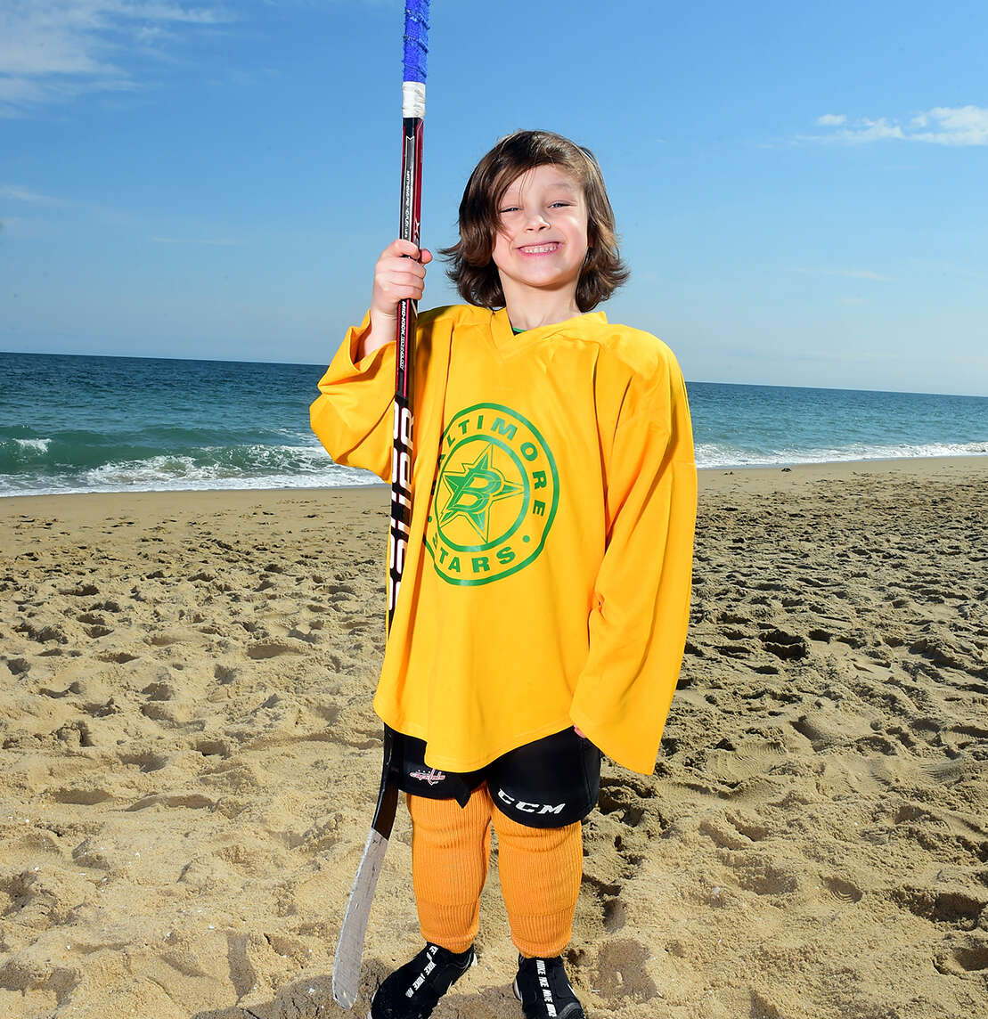 Child hockey player posing on the beach